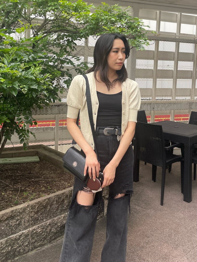 ブラック系のデニムパンツ、ブラック系のキャミソール、ホワイト系のカーディガン/ボレロを着用したレディースの春コーディネートの3枚目の写真