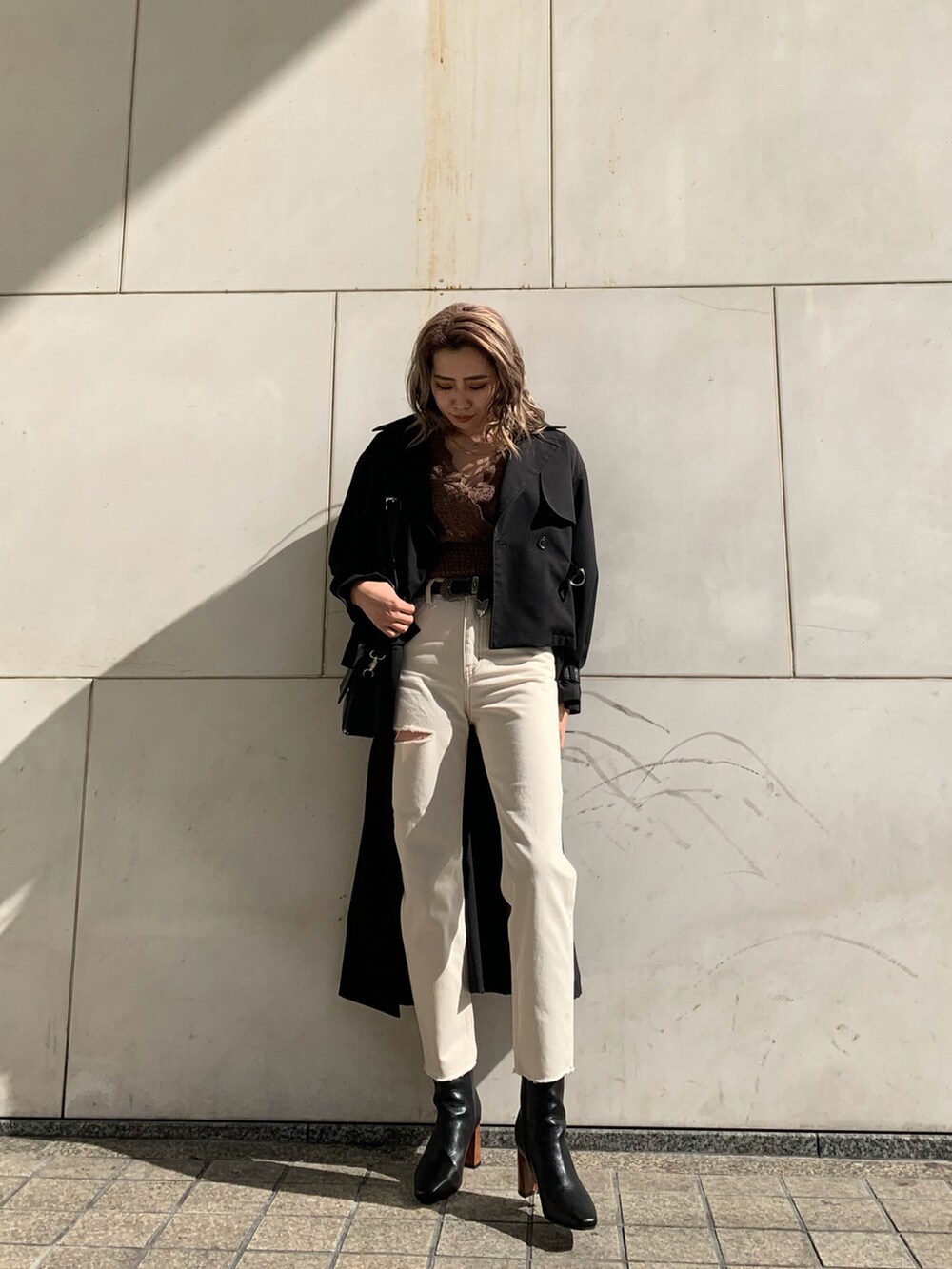 ブラック系のショルダーバッグ、ブラック系のトレンチコート、ホワイト系のデニムパンツを着用したレディースの冬コーディネートの6枚目の写真