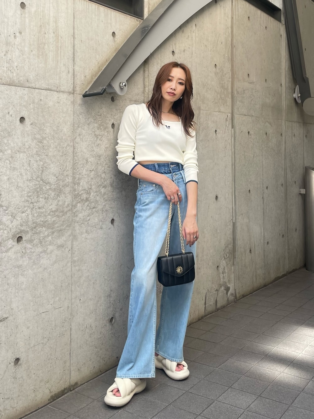 ホワイト系のニット/セーター、ブルー系のデニムパンツ、ブラック系のショルダーバッグを着用したレディースの夏コーディネートの3枚目の写真