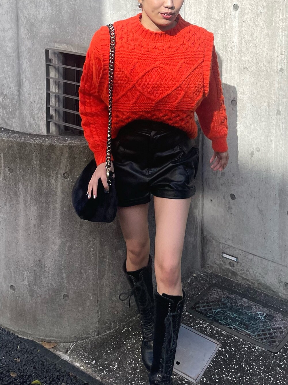 オレンジ系のニット/セーター、ブラック系のその他パンツ、ブラック系のショルダーバッグを着用したレディースの冬コーディネートの4枚目の写真
