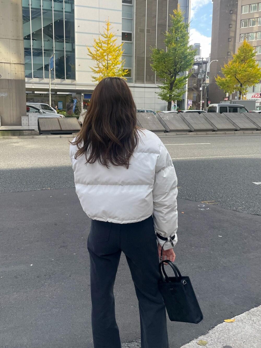 ホワイト系のダウンジャケット/コート、ブラック系のTシャツ/カットソー、ブラック系のショルダーバッグを着用したレディースの秋コーディネートの5枚目の写真