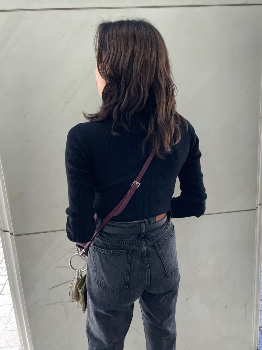 レッド系のショルダーバッグ、ブラック系のデニムパンツ、ブラック系のニット/セーターを着用したレディースの秋コーディネートの5枚目の写真