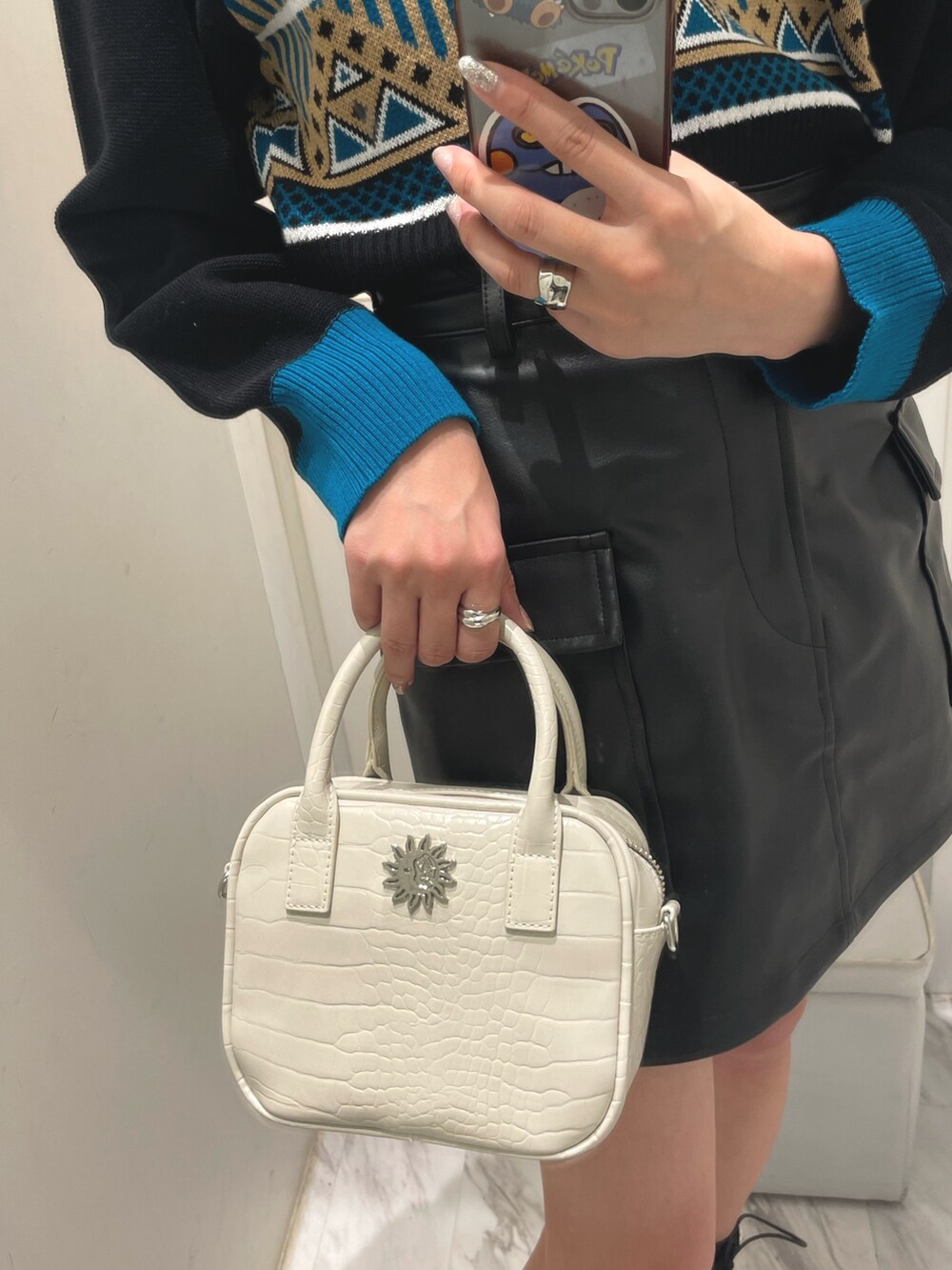 ブルー系のニット/セーター、ブラック系のスカート、ホワイト系のショルダーバッグを着用したレディースの冬コーディネートの6枚目の写真