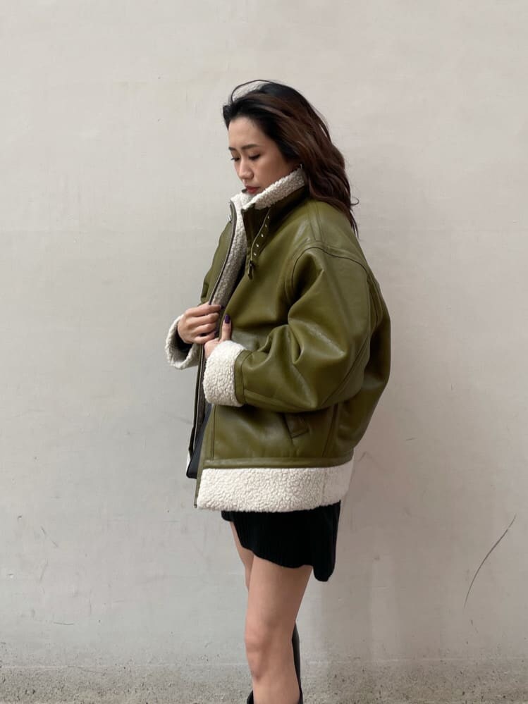 グリーン系のブルゾン、ブラック系のショルダーバッグ、ブラック系のワンピースを着用したレディースの冬コーディネートの6枚目の写真