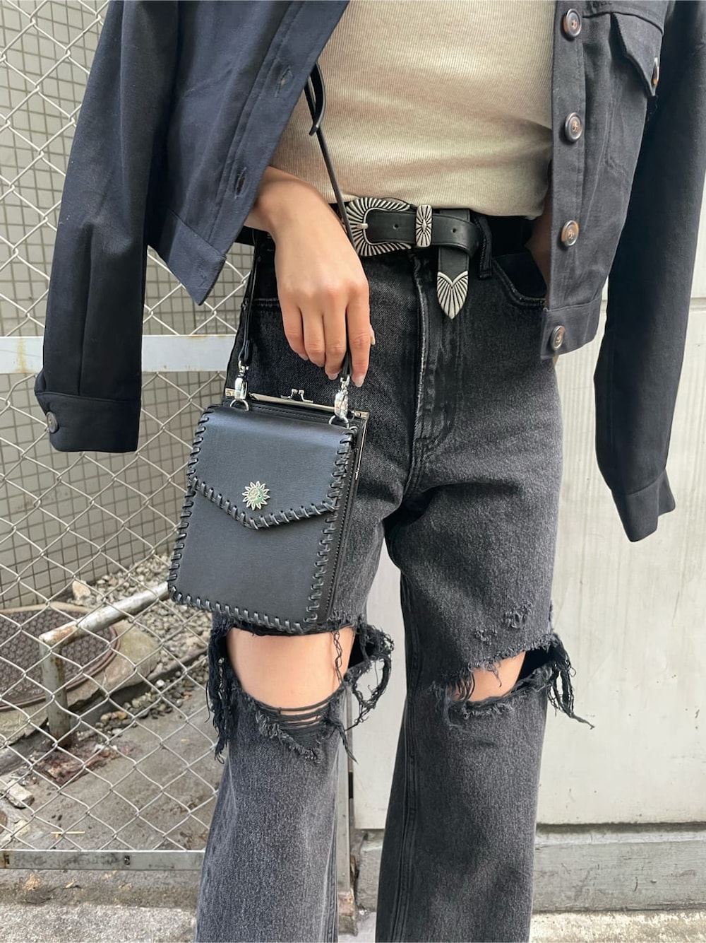 ブラック系のショルダーバッグ、ブラック系のデニムパンツ、ブラック系のブーツを着用したレディースの春コーディネートの6枚目の写真