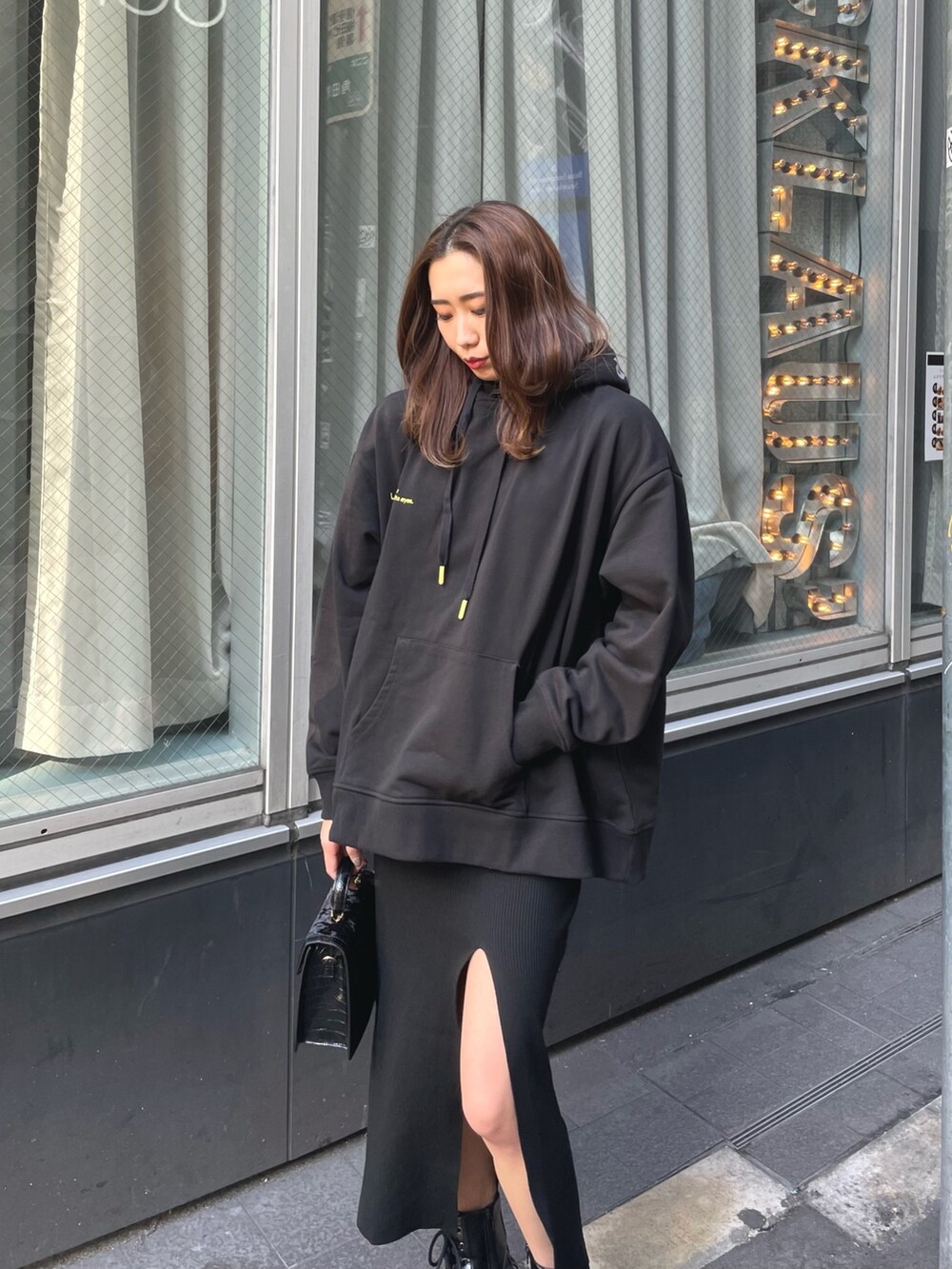 ブラック系のパーカー、ブラック系のショルダーバッグ、ブラック系のワンピースを着用したレディースの冬コーディネートの2枚目の写真