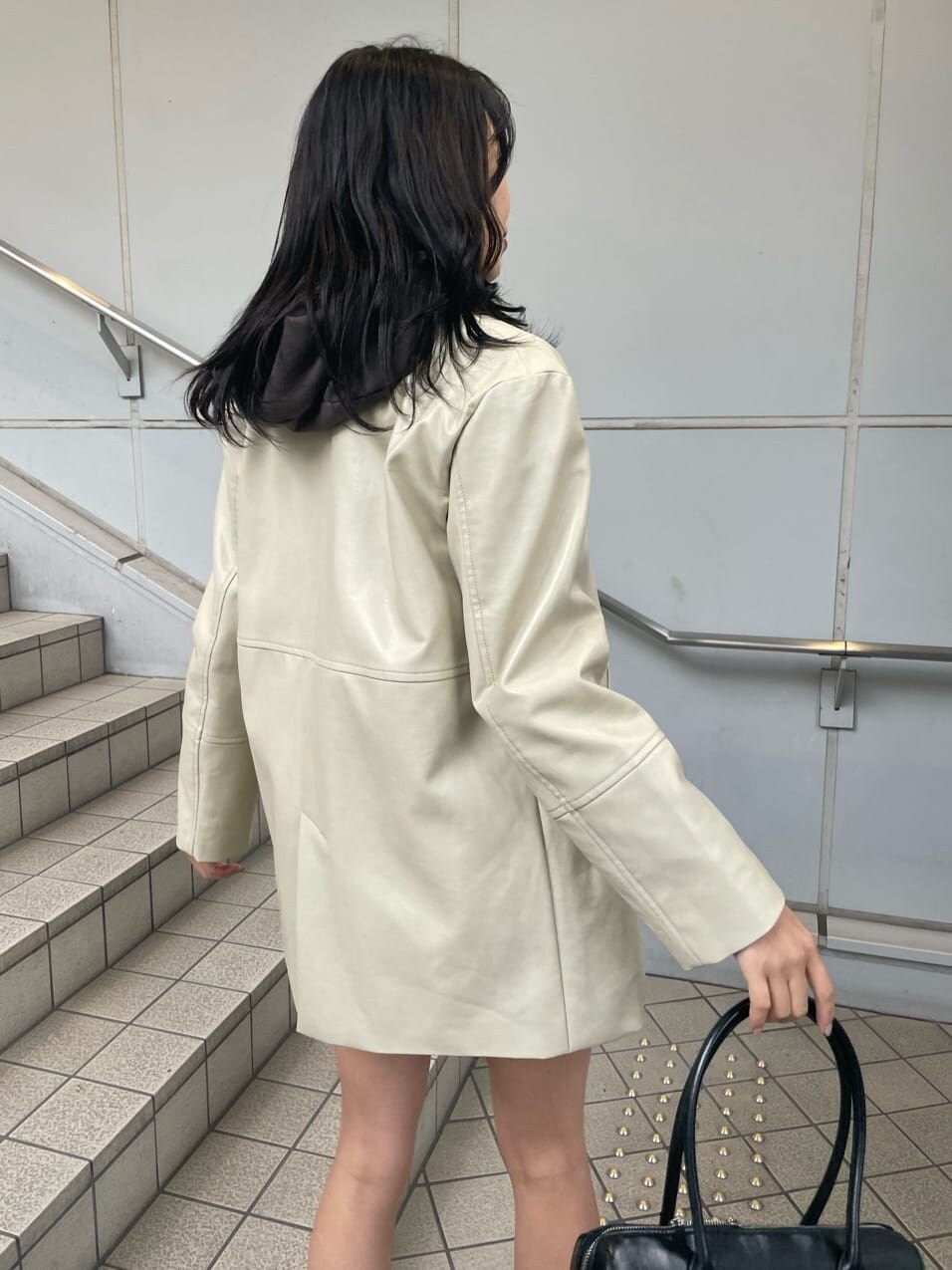 ホワイト系のテーラードジャケット、ブラック系のスカート、ブラック系のブーツを着用したレディースの冬コーディネートの7枚目の写真