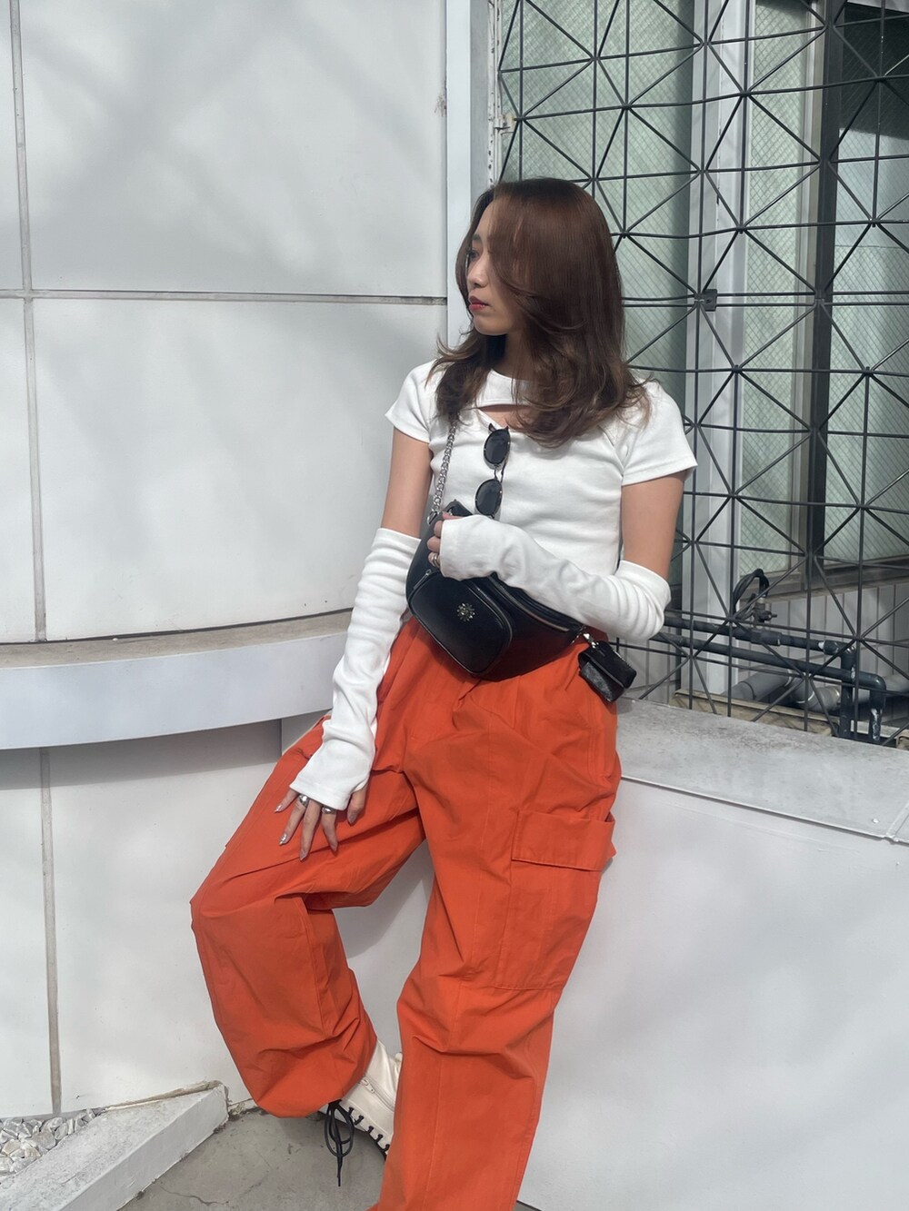 オレンジ系のカーゴパンツ、ホワイト系のTシャツ/カットソー、ホワイト系のブーツを着用したレディースの春コーディネートの2枚目の写真