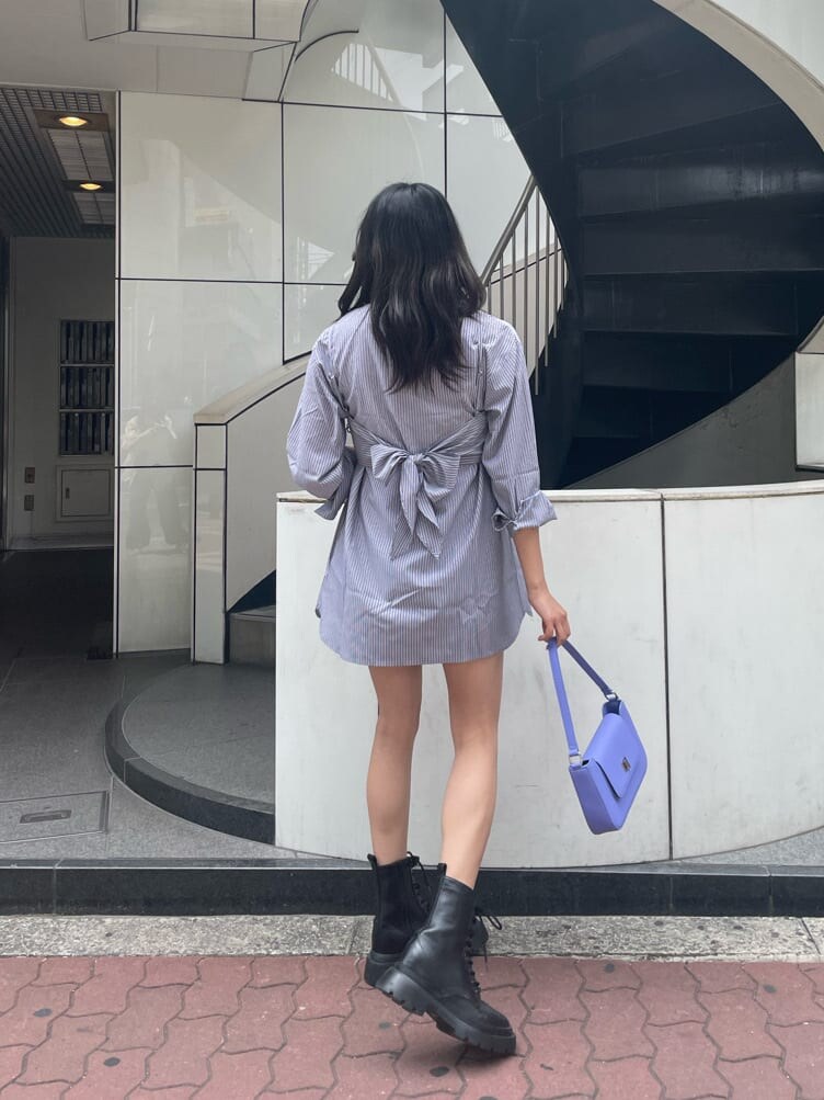 ブラック系のブーツ、ブラック系のワンピース、パープル系のショルダーバッグを着用したレディースの春コーディネートの2枚目の写真