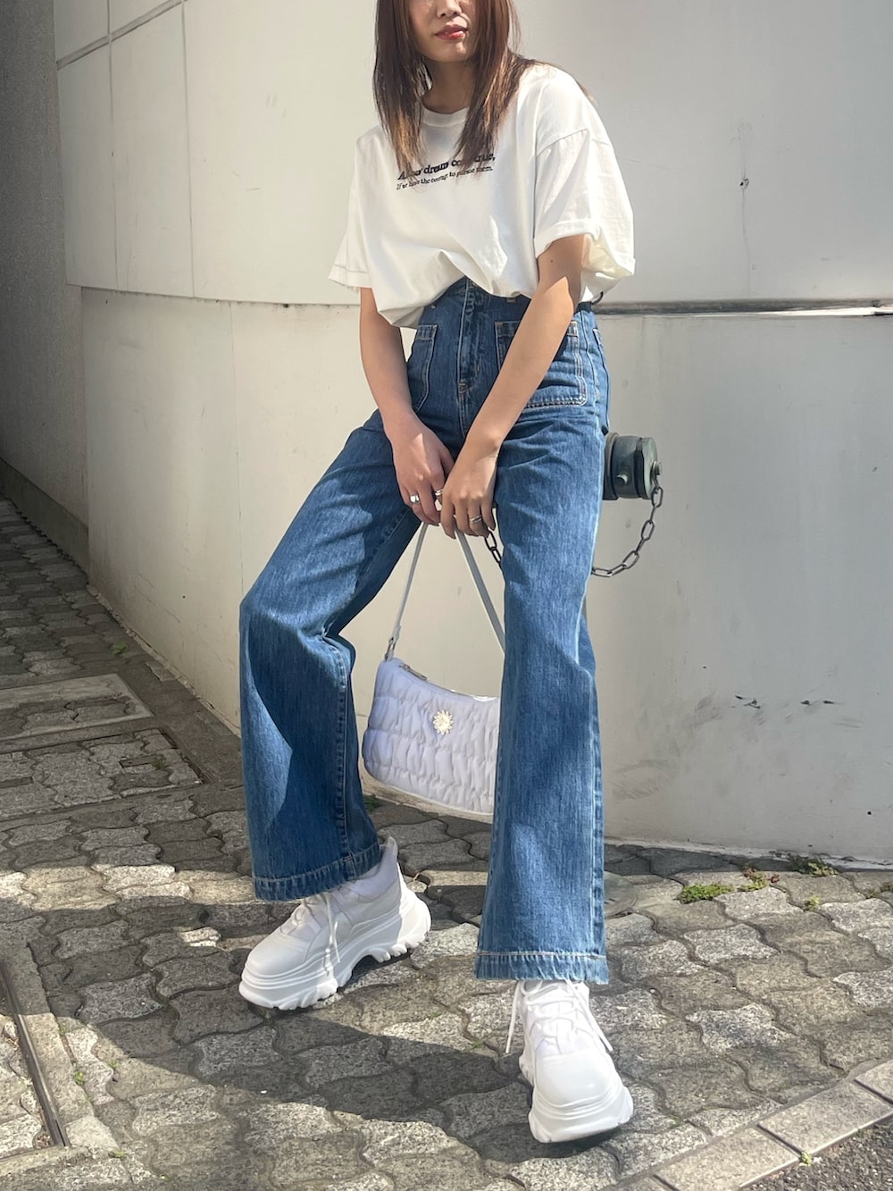 ホワイト系のTシャツ/カットソー、ブルー系のデニムパンツ、ホワイト系のハンドバッグを着用したレディースの春コーディネートの5枚目の写真