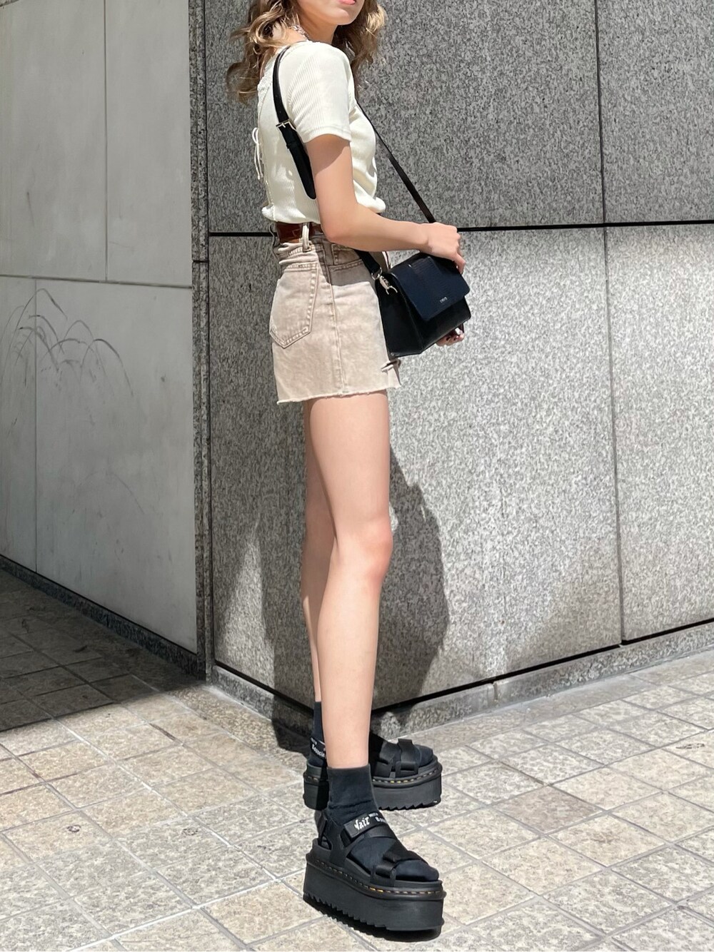 ブラック系のショルダーバッグ、ベージュ系のデニムパンツ、ホワイト系のTシャツ/カットソーを着用したレディースの春コーディネートの4枚目の写真