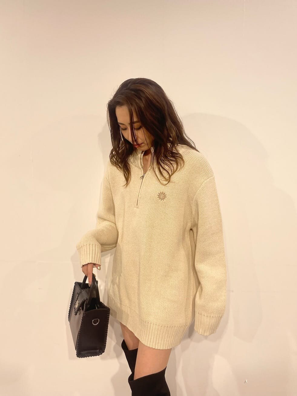 ブラック系のショルダーバッグ、ホワイト系のニット/セーター、ブラック系のブーツを着用したレディースの秋コーディネートの3枚目の写真