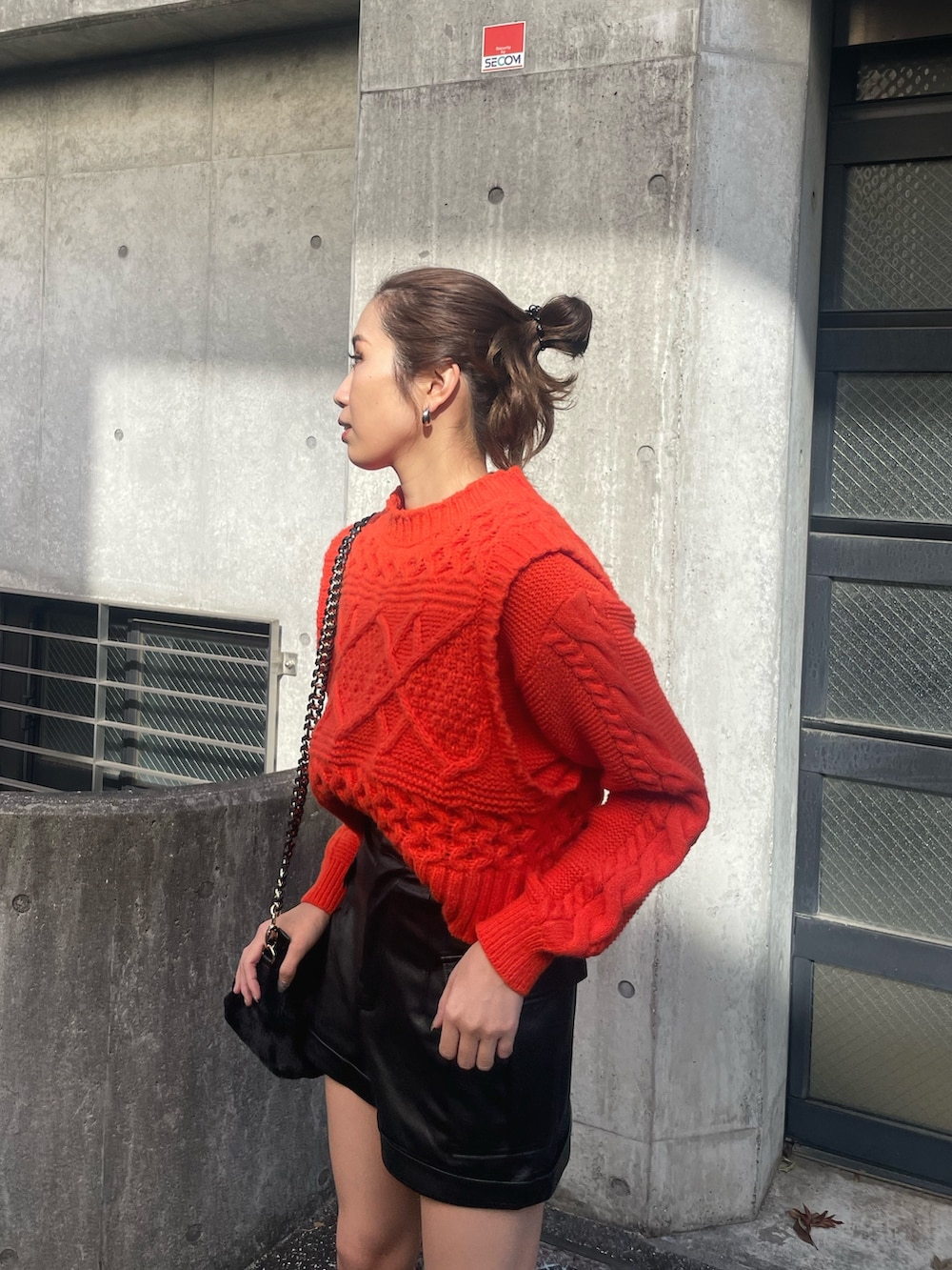 オレンジ系のニット/セーター、ブラック系のその他パンツ、ブラック系のショルダーバッグを着用したレディースの冬コーディネートの5枚目の写真