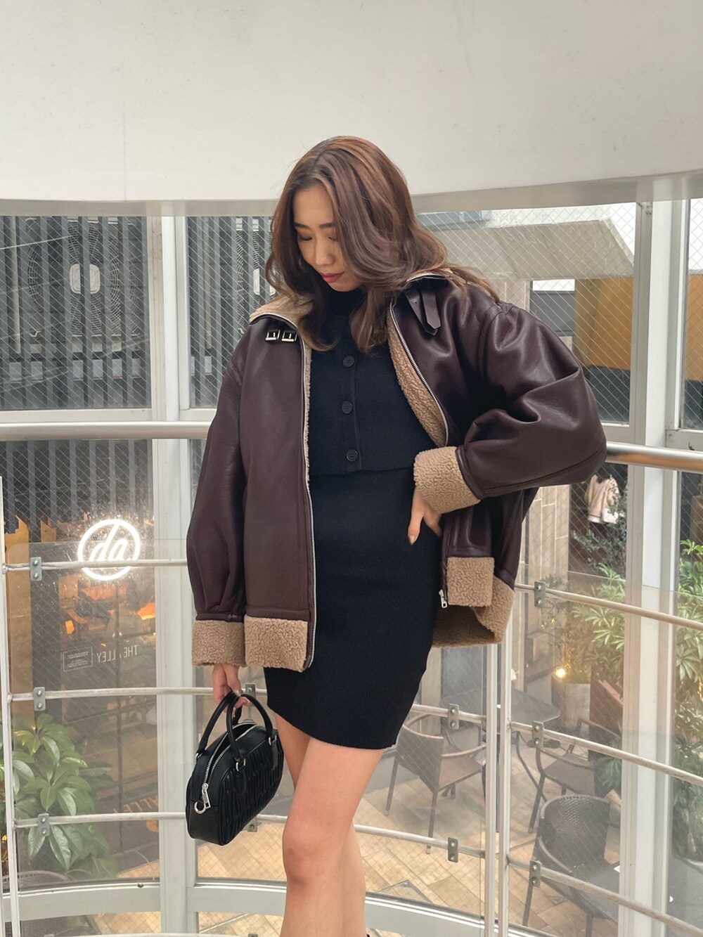 ブラック系のブーツ、ブラック系のショルダーバッグ、ブラウン系のブルゾンを着用したレディースの冬コーディネートの3枚目の写真