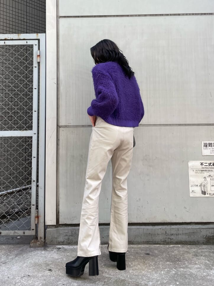 ブラック系のブーツ、パープル系のニット/セーター、ブラック系のショルダーバッグを着用したレディースの冬コーディネートの2枚目の写真