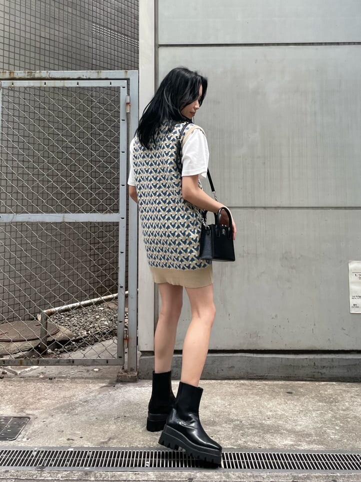 ブラック系のブーツ、ベージュ系のニット/セーター、ホワイト系のTシャツ/カットソーを着用したレディースの春コーディネートの3枚目の写真