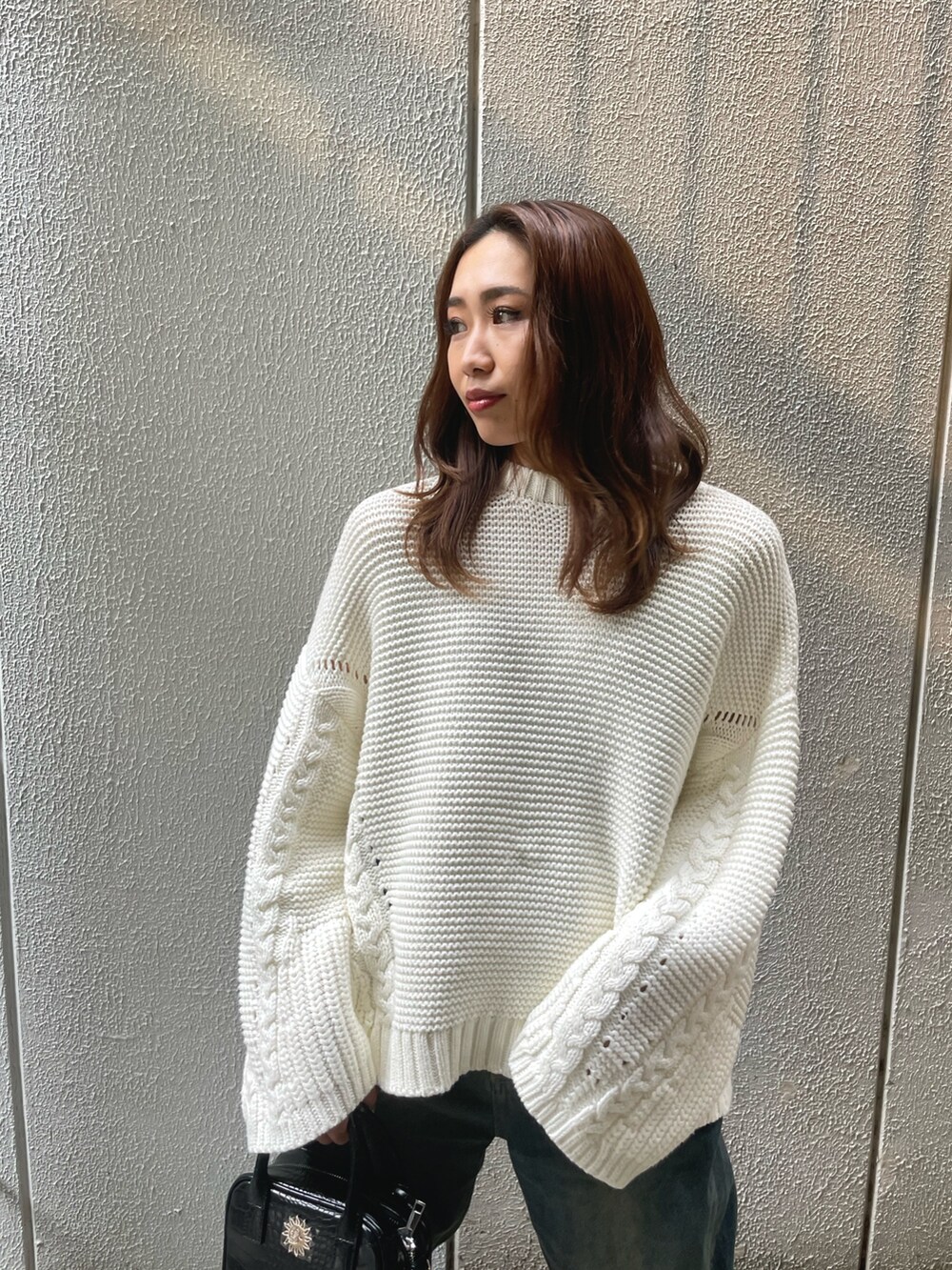 ホワイト系のニット/セーター、ブルー系のデニムパンツ、ホワイト系のショルダーバッグを着用したレディースの冬コーディネートの3枚目の写真