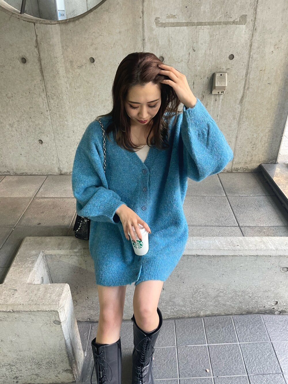 ブルー系のカーディガン/ボレロ、ブラック系のショルダーバッグ、ブラウン系のブーツを着用したレディースの秋コーディネートの5枚目の写真