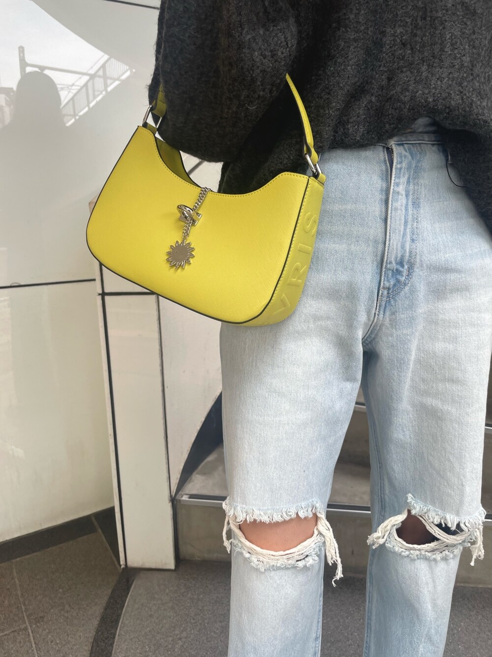 グレー系のニット/セーター、イエロー系のハンドバッグ、ブルー系のデニムパンツを着用したレディースの秋コーディネートの6枚目の写真