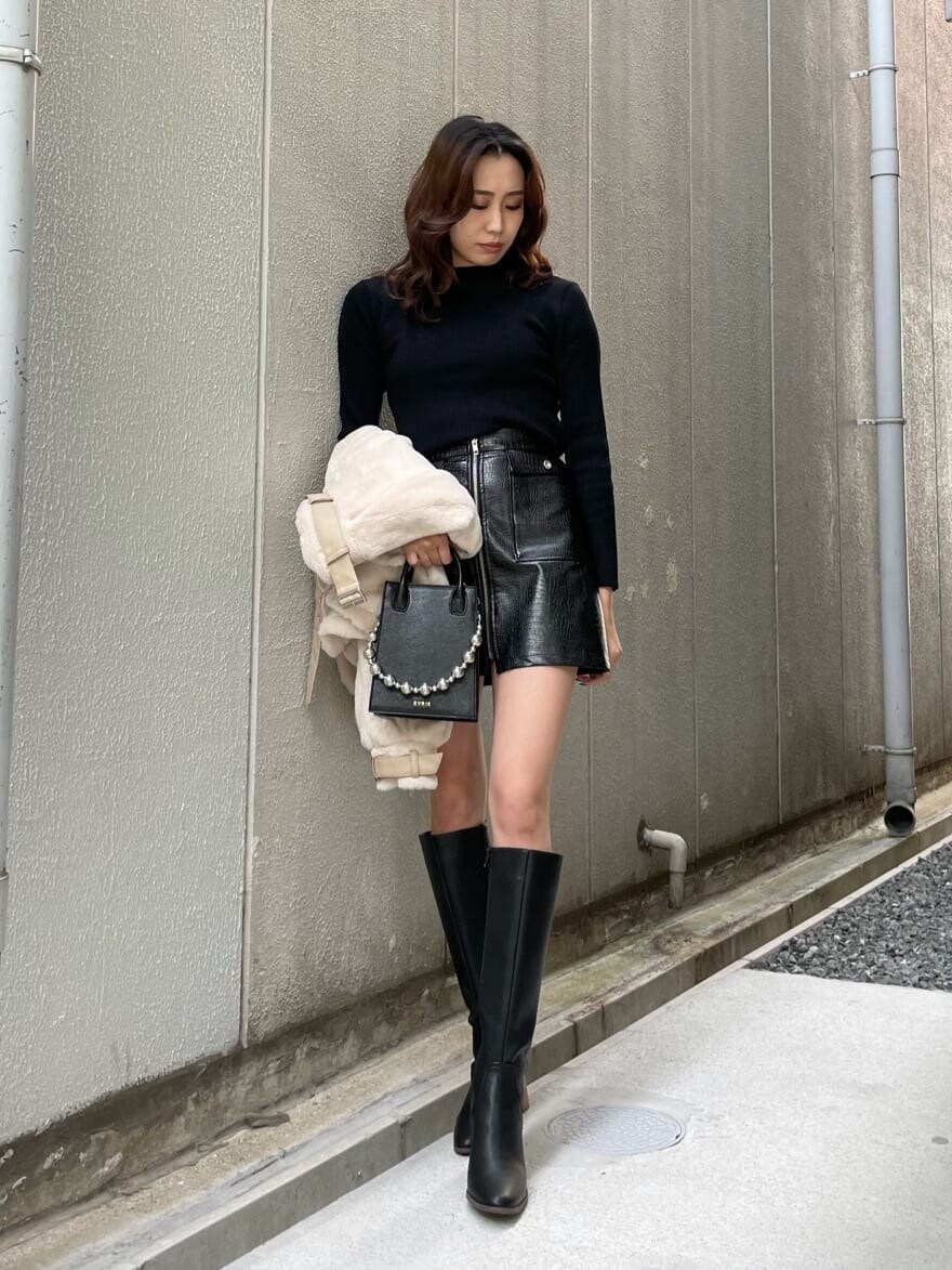 ブラック系のニット/セーター、ホワイト系のブルゾン、ブラック系のスカートを着用したレディースの秋コーディネートの2枚目の写真