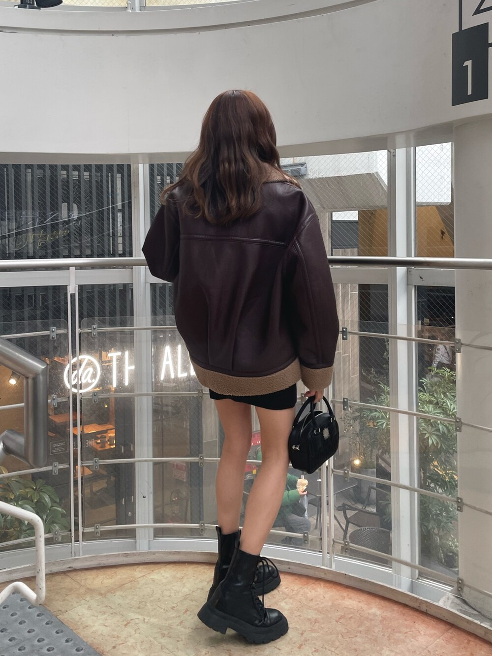 ブラック系のブーツ、ブラック系のショルダーバッグ、ブラウン系のブルゾンを着用したレディースの冬コーディネートの2枚目の写真