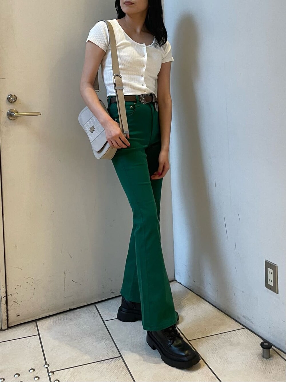 ブラック系のブーツ、ホワイト系のTシャツ/カットソー、グリーン系のデニムパンツを着用したレディースの春コーディネートの2枚目の写真