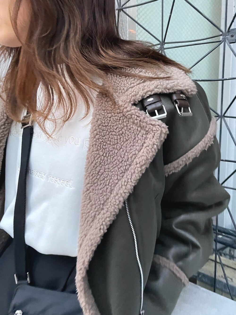 グリーン系のブルゾン、ホワイト系のスウェット、ブラック系のスラックスを着用したレディースの冬コーディネートの5枚目の写真