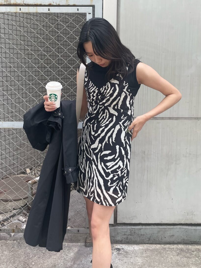 ブラック系のブーツ、ブラック系のトレンチコート、ブラック系のワンピースを着用したレディースの春コーディネートの5枚目の写真