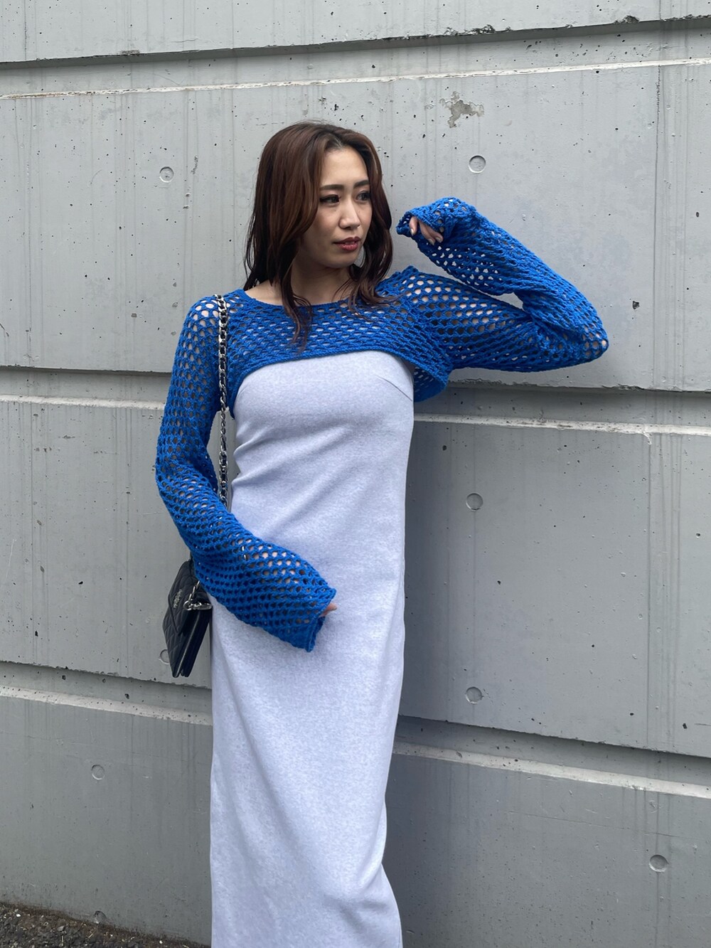 ブルー系のニット/セーター、ブラック系のショルダーバッグ、グレー系のワンピースを着用したレディースの春コーディネートの4枚目の写真