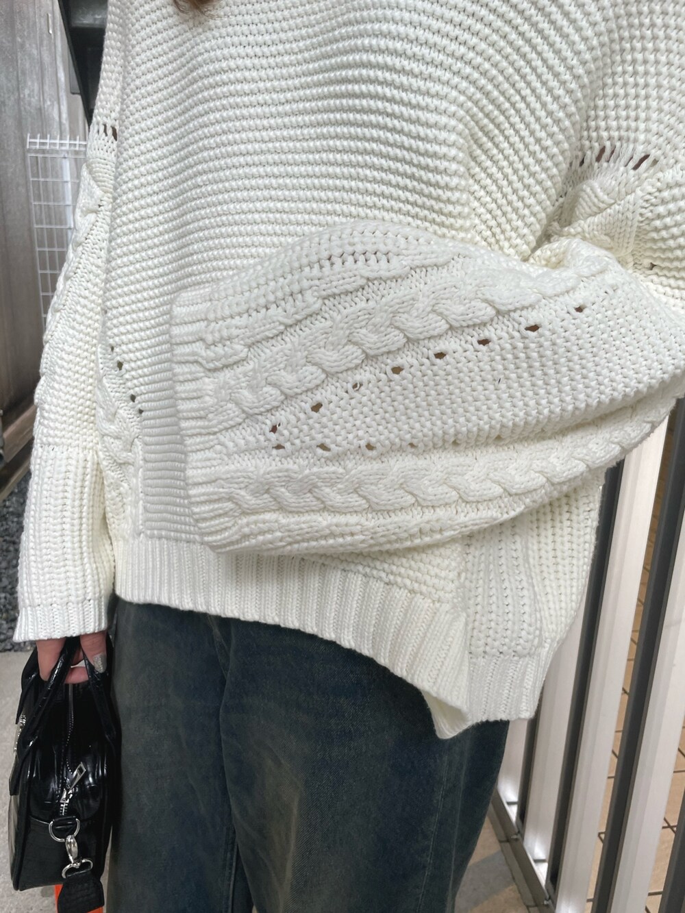 ホワイト系のニット/セーター、ブルー系のデニムパンツ、ホワイト系のショルダーバッグを着用したレディースの冬コーディネートの4枚目の写真