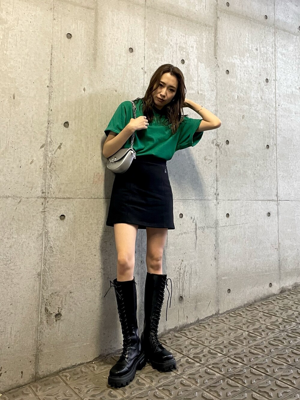 グリーン系のTシャツ/カットソー、ブラック系のスカート、ブラック系のブーツを着用したレディースの夏コーディネートの2枚目の写真