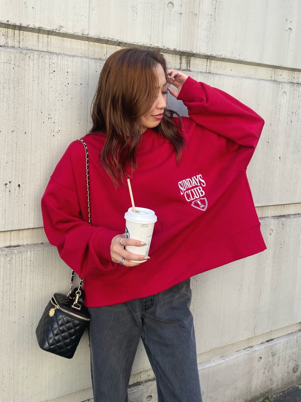 レッド系のスウェット、ブラック系のデニムパンツを着用したレディースの夏コーディネートの5枚目の写真