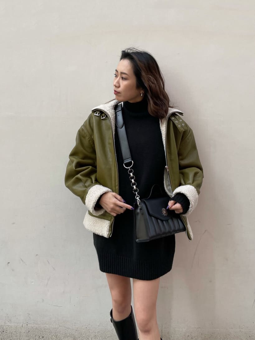 グリーン系のブルゾン、ブラック系のショルダーバッグ、ブラック系のワンピースを着用したレディースの冬コーディネートの2枚目の写真