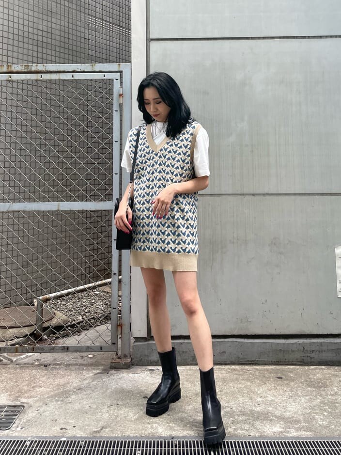 ブラック系のブーツ、ベージュ系のニット/セーター、ホワイト系のTシャツ/カットソーを着用したレディースの春コーディネートの2枚目の写真