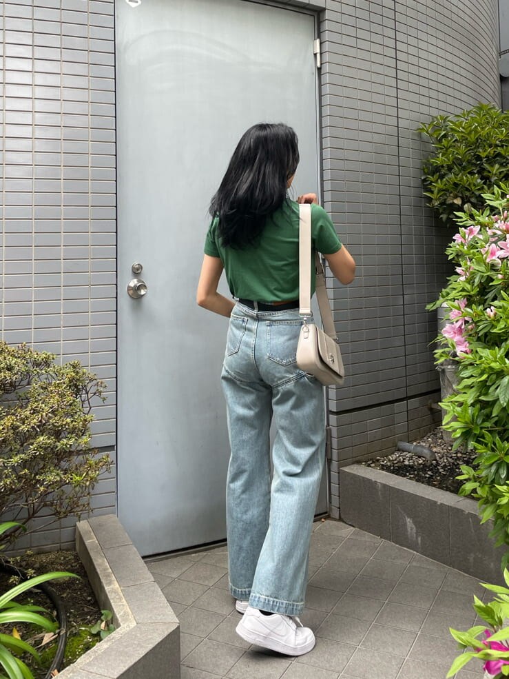 グリーン系のTシャツ/カットソー、ホワイト系のショルダーバッグ、ブルー系のデニムパンツを着用したレディースの春コーディネートの3枚目の写真