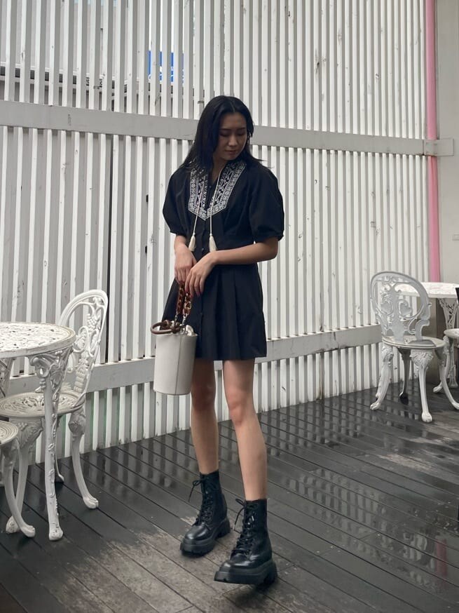 ブラック系のブーツ、ブラック系のワンピース、ホワイト系のショルダーバッグを着用したレディースの春コーディネートの3枚目の写真