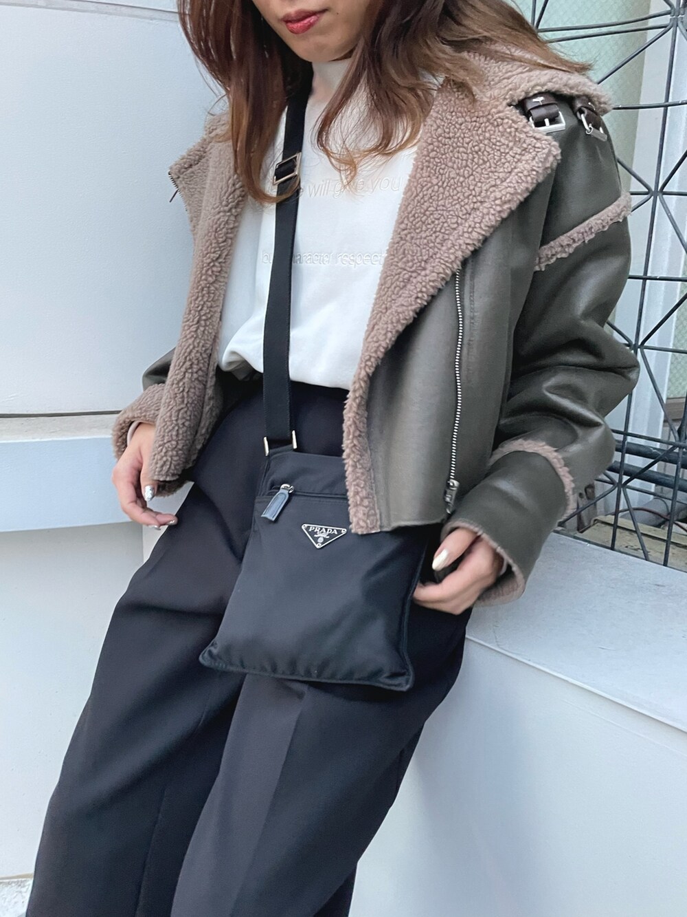 グリーン系のブルゾン、ホワイト系のスウェット、ブラック系のスラックスを着用したレディースの冬コーディネートの4枚目の写真