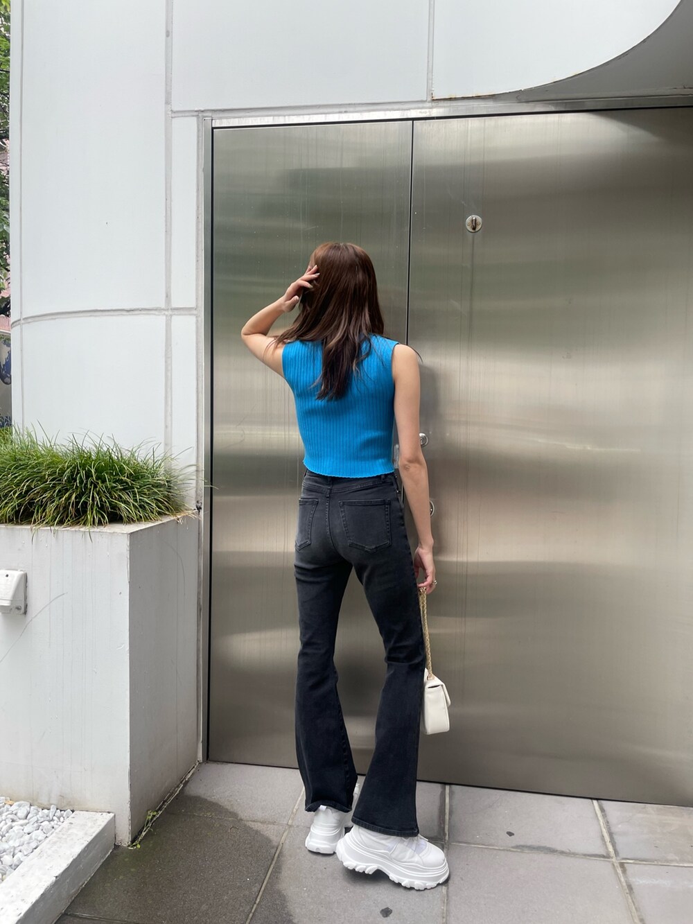 ブルー系のタンクトップ、ブラック系のデニムパンツ、ホワイト系のスニーカーを着用したレディースの春コーディネートの3枚目の写真