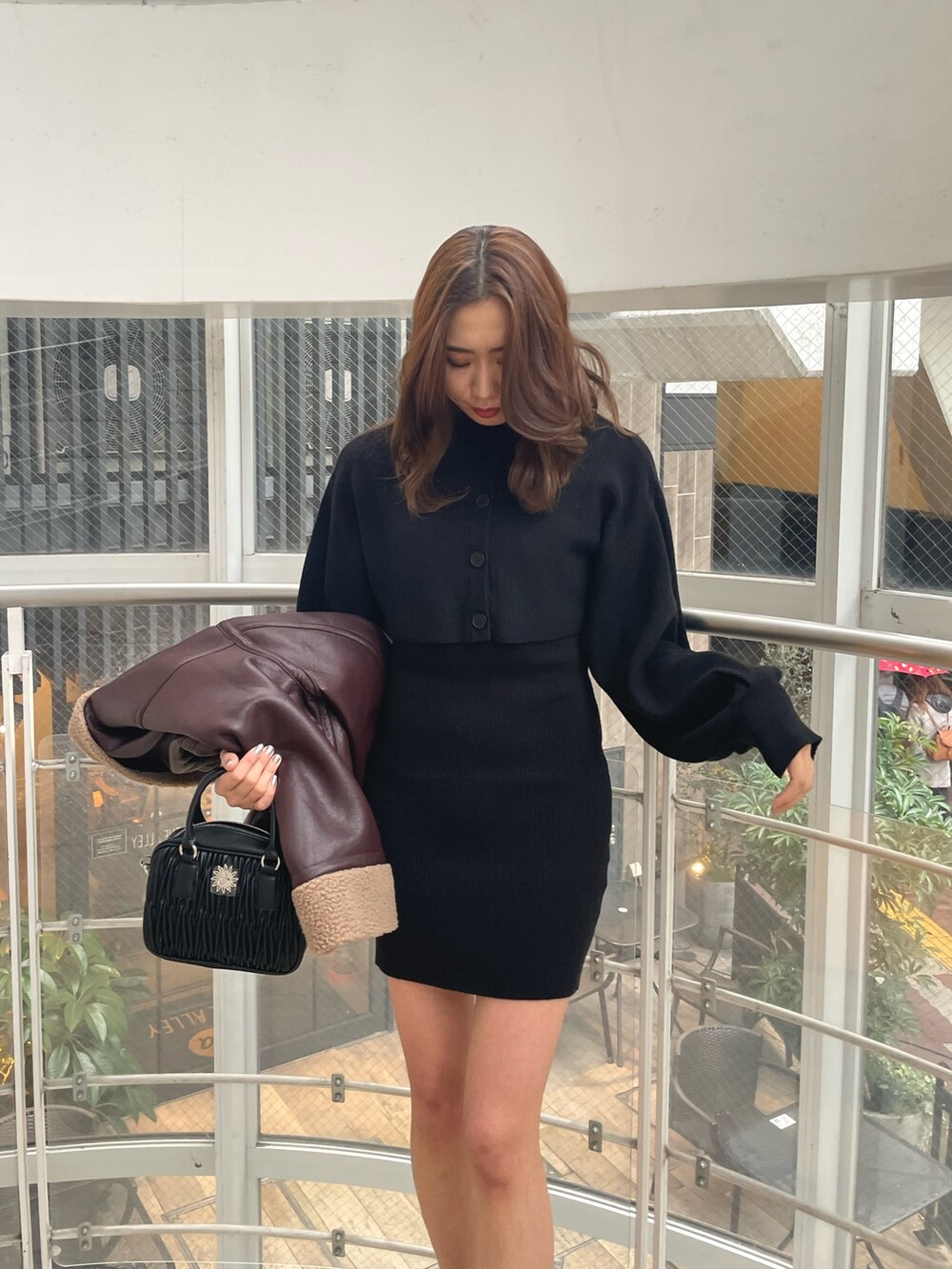 ブラック系のブーツ、ブラック系のショルダーバッグ、ブラウン系のブルゾンを着用したレディースの冬コーディネートの4枚目の写真