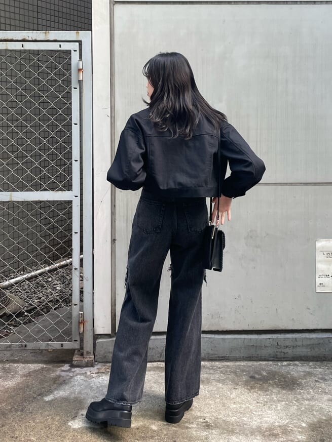 ブラック系のショルダーバッグ、ブラック系のデニムパンツ、ブラック系のブーツを着用したレディースの春コーディネートの2枚目の写真