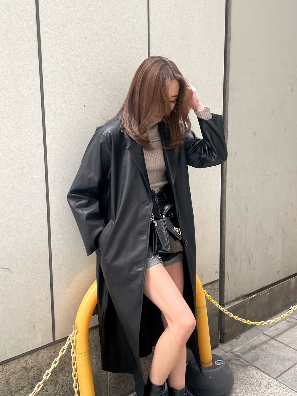グレー系のニット/セーター、ブラック系のチェスターコート、ブラック系のデニムパンツを着用したレディースの冬コーディネートの5枚目の写真