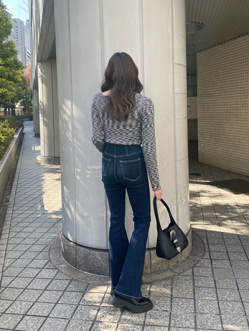 ブラック系のブルゾン、ブラック系のニット/セーター、ブルー系のデニムパンツを着用したレディースの冬コーディネートの6枚目の写真