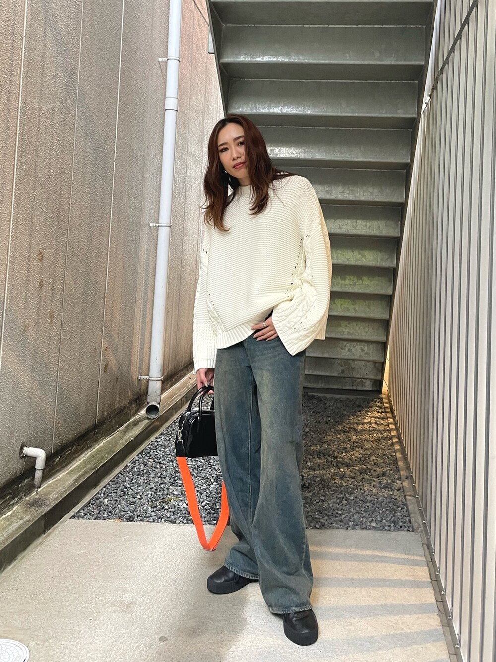 ホワイト系のニット/セーター、ブルー系のデニムパンツ、ホワイト系のショルダーバッグを着用したレディースの冬コーディネートの2枚目の写真