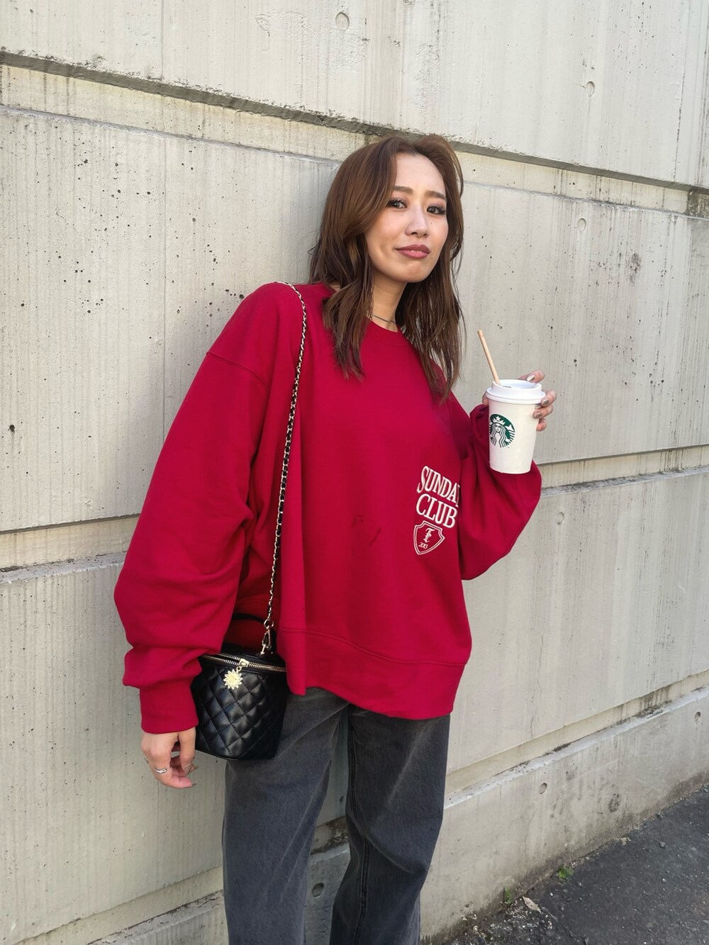 レッド系のスウェット、ブラック系のデニムパンツを着用したレディースの夏コーディネートの3枚目の写真