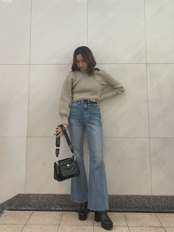 ブルー系のデニムパンツ、ホワイト系のニット/セーター、ブラック系のベルトを着用したレディースの秋コーディネートの2枚目の写真