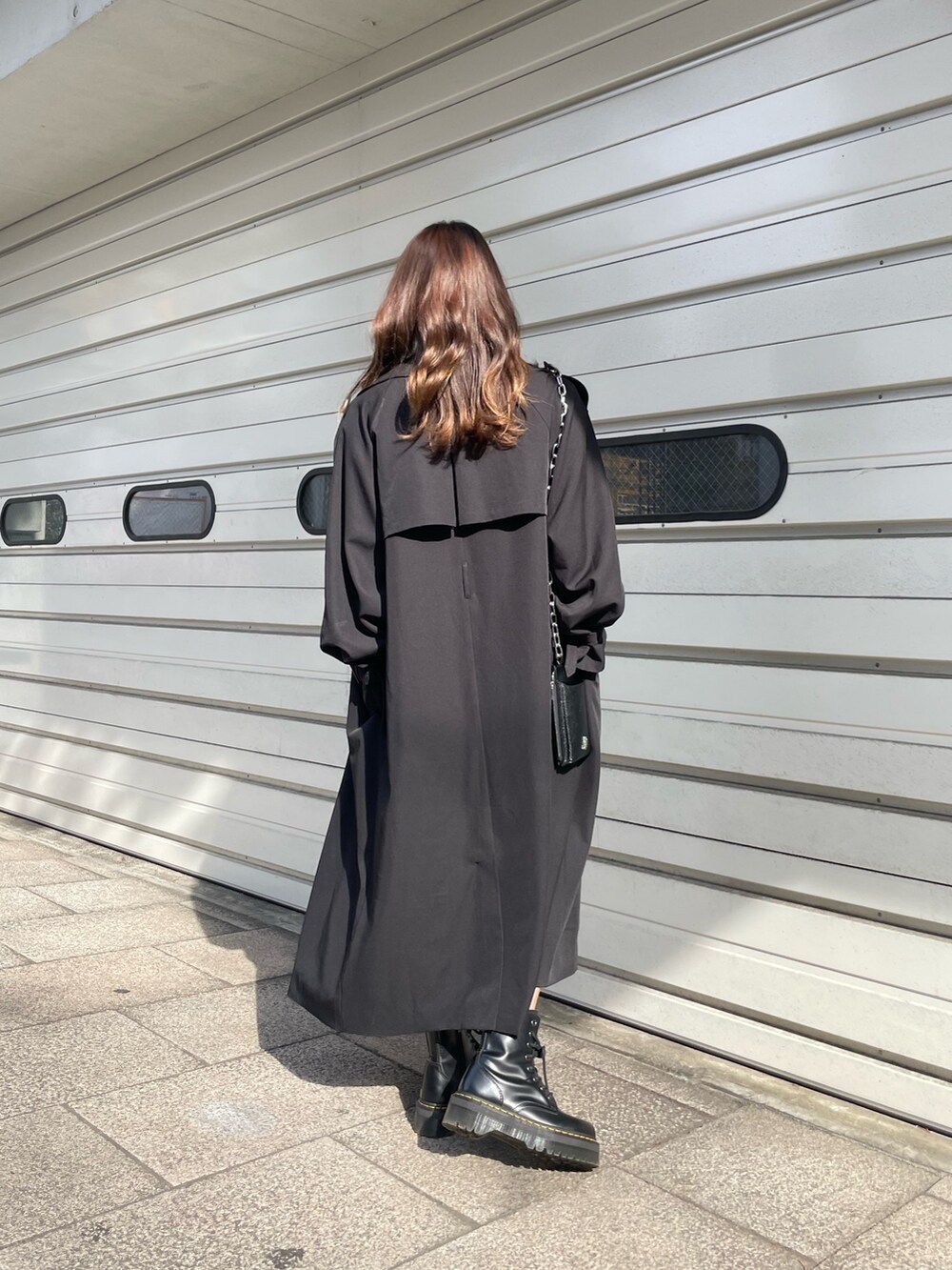 ブラック系のショルダーバッグ、ブラック系のトレンチコート、ホワイト系のワンピースを着用したレディースの冬コーディネートの7枚目の写真