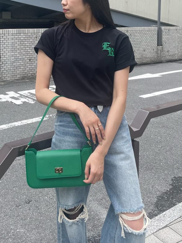 グリーン系のショルダーバッグ、ブルー系のデニムパンツ、ブラック系のスニーカーを着用したレディースの夏コーディネートの3枚目の写真