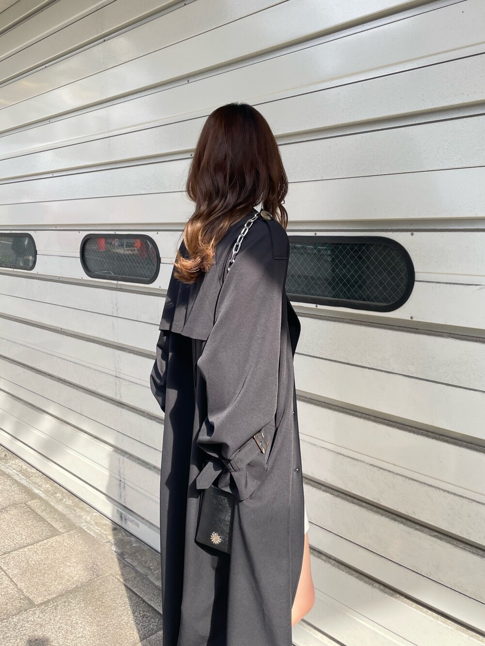 ブラック系のショルダーバッグ、ブラック系のトレンチコート、ホワイト系のワンピースを着用したレディースの冬コーディネートの6枚目の写真