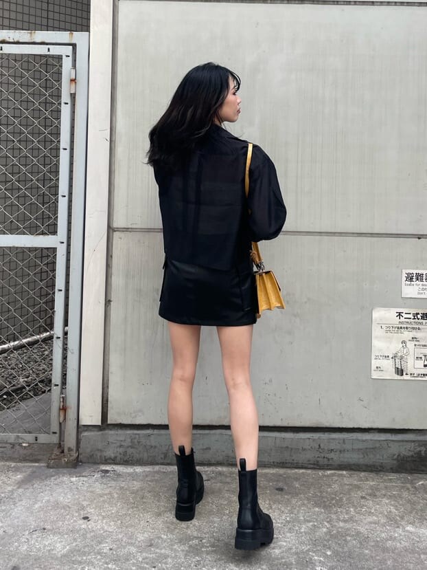 ホワイト系のキャミソール、ブラック系のブーツ、ブラック系のスカートを着用したレディースの春コーディネートの2枚目の写真