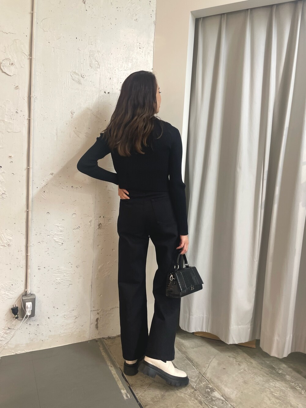 ブラック系のニット/セーター、ブラック系のショルダーバッグ、ホワイト系のブーツを着用したレディースの秋コーディネートの2枚目の写真